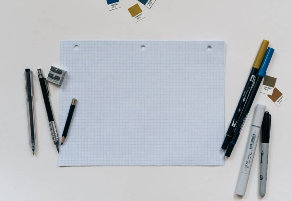 sheet of graph paper on table with pens