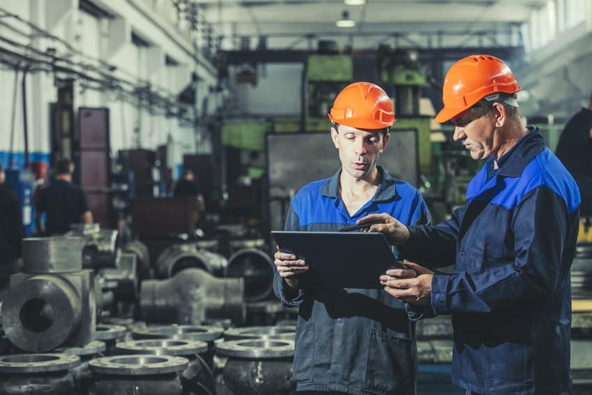 two factory workers pointing to tablet
